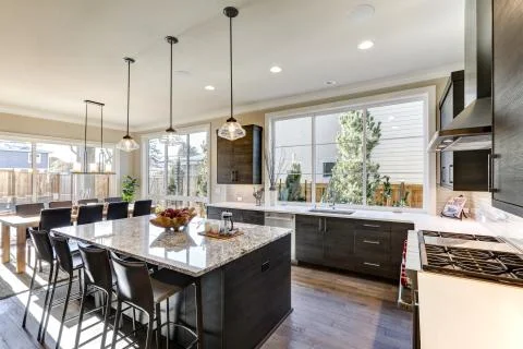 Modern gray kitchen features dark gray flat front cabinets paired with white qua Stock Photos