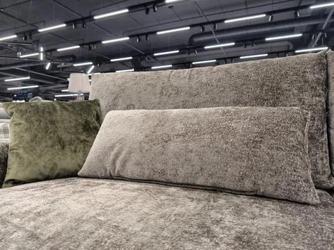 A modern gray settee with one long cushion and a dark green square pillow, .. Stock Photos