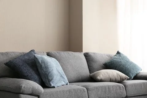 Modern gray sofa with assorted blue and beige throw pillows in a minimalist l Stock Photos