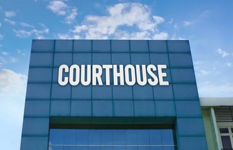 Modern green facade with a large COURTHOUSE sign against a cloudy blue sky. Stock Photos