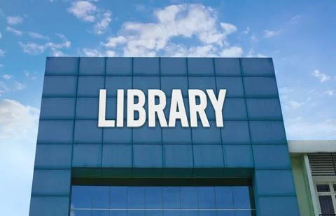 Modern green facade with a large LIBRARY sign against a cloudy blue sky. Stock Photos