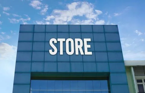 Modern green facade with a large STORE sign against a cloudy blue sky. Stock Photos