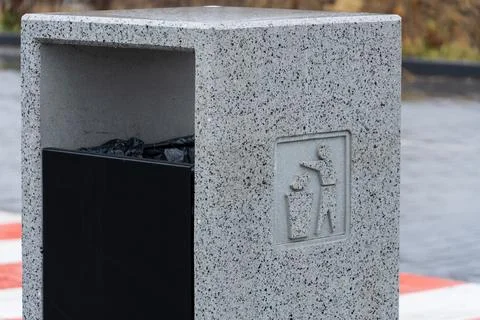 A modern grey garbage container stands in an urban area, inviting passersby.. Stock Photos