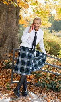 Modern guy in kilt smiling while talking on mobile phone Foto stock