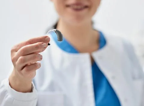 Modern hearing aid in hands of smiling audiologist, close-up, soft focus. Hea Foto stock