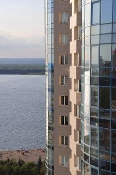 Modern high building on the background of the river, sandy beach on the Volga Stock Photos