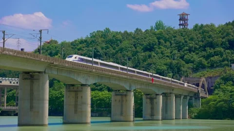 Modern high-speed train runs across the railway bridge over the river surface. Stock-Footage 334159893