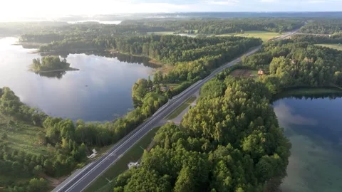 Modern highway cutting through serene lakeside forest Stock Footage 345593907