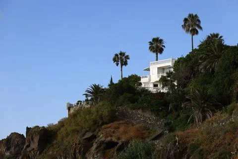 Modern hillside house with white multi level terraces positioned above rock.. Fotos Stock
