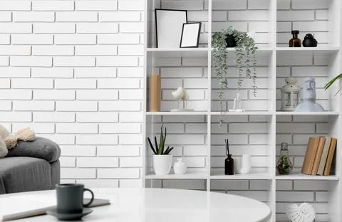 Modern home interior with white brick wall, minimalist shelf decor, and a coz Stock Photos