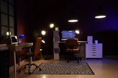 Modern home office with computer and laptop at night Stock-Fotos