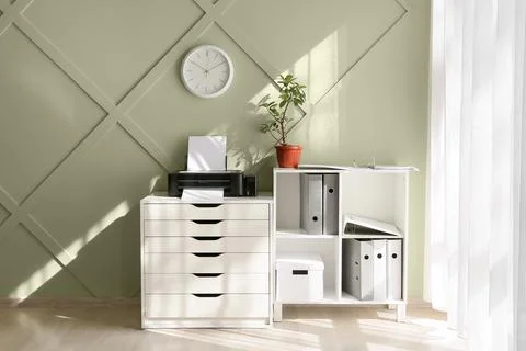 Modern home office interior with printer, file cabinet, and green wall decor  Stockfoto's