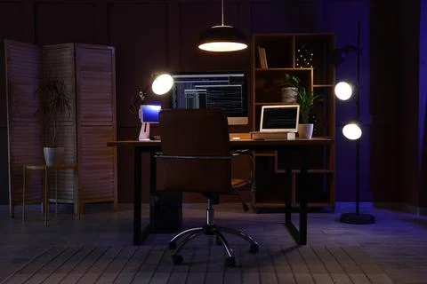 Modern home office workspace with computer screens and desk lamps Stock Photos