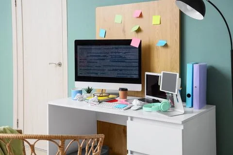 Modern home office workspace with computer monitor displaying code laptop tab Foto stock