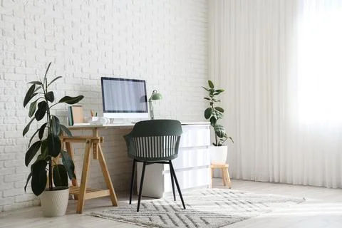 Modern home office workspace with computer monitor, green chair, and indoor p Stock Photos