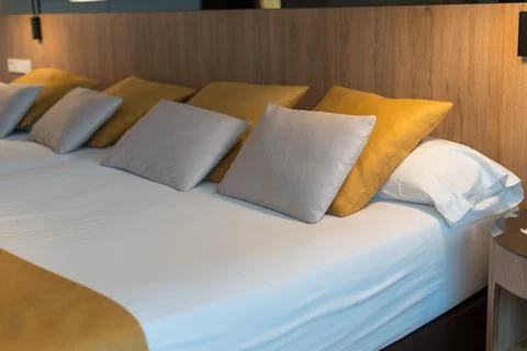 Modern hotel bed with white bedding and decorative pillows Stock Photos