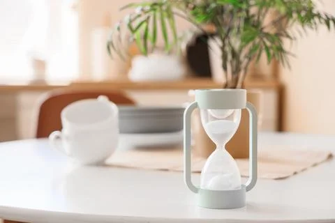 Modern hourglass timer with flowing white sand on a clean white tabletop, tim Stock Photos