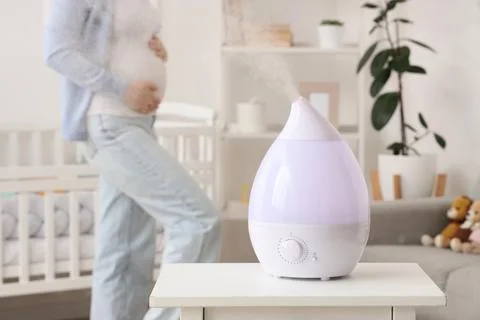 Modern humidifier on bedside table in children's bedroom with pregnant woman Stock Photos