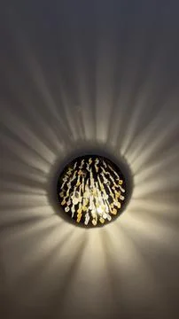 Modern illuminated wall sconce casting dramatic radial ray patterns of warm Stock Photos