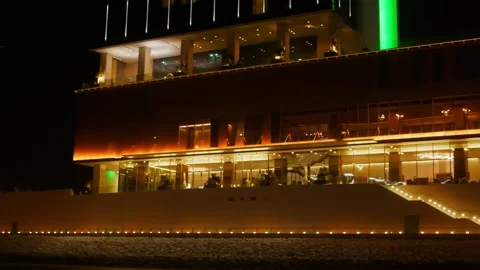 Modern illuminated waterfront building at night reflecting in calm water Stock Footage 337482404