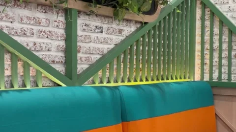Modern Indoor Cafe Seating with Green Wooden Slats and Teal-Yellow Upholstery Stock Footage 330145178