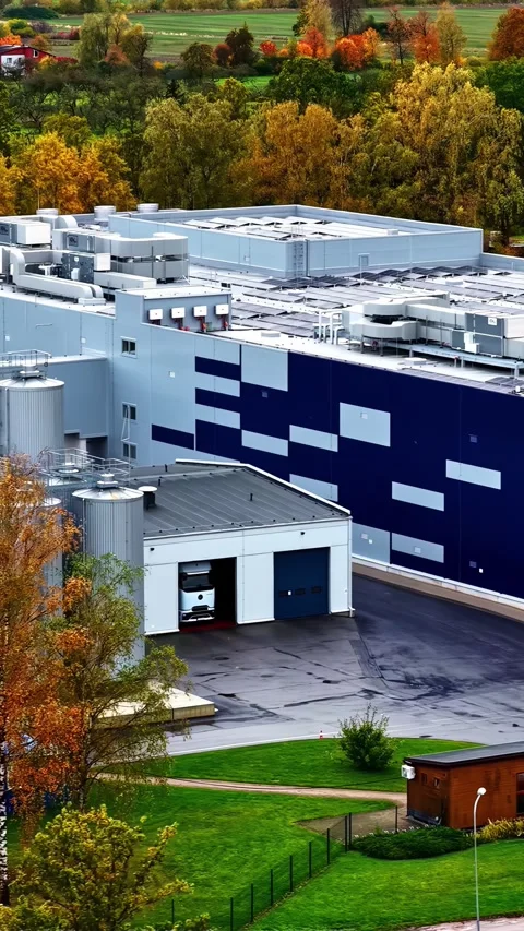 Modern industrial building with a loading dock and trucks in autumn, vertical Stock Footage 336240402