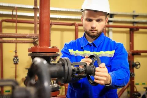 Modern industrial machine operator working in heating station. Worker turns g Stock Photos