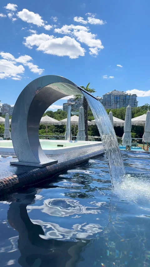 Modern infinity pool deck featuring elegant metal water feature 库存影片 337315789