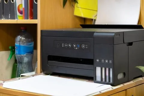 Modern inkjet printer with an integrated ink tank system sitting on a woode.. Stock Photos