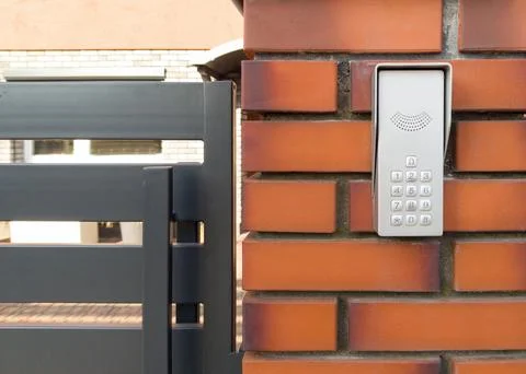 Modern Intercom Keypad on Brick Wall by Metal Gate Stock Photos