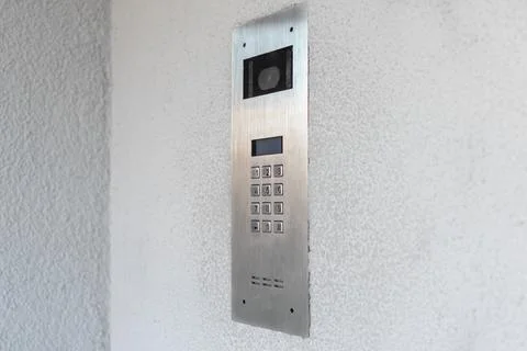 Modern intercom system with camera and keypad on textured white wall Stock Photos