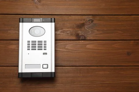 Modern intercom system with camera on wooden background, top view. Space for  Foto stock