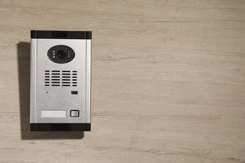 Modern intercom system with camera on wooden background, top view. Space for  Foto stock
