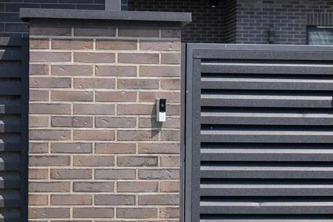 Modern intercom system mounted on a brick wall next to a slatted fence crea.. Stock Photos