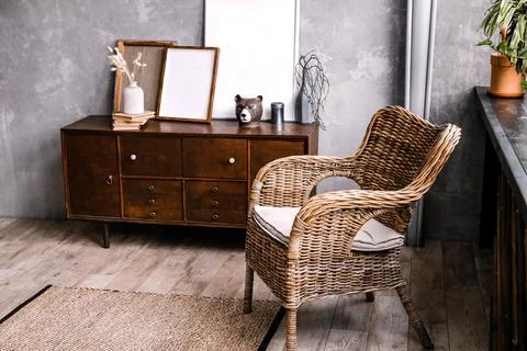 Modern interior featuring a wicker chair beside a wooden sideboard with Stock Photos