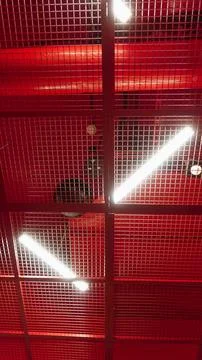 Modern Interior Red Ceiling Grid Structure, Neon Lights, and Industrial Pipes Stock Photos