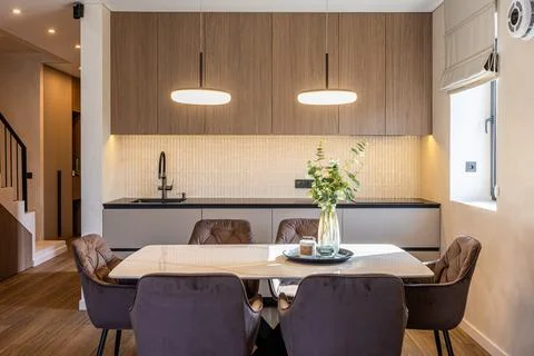 Modern kitchen and dining area with wooden cabinets and pendant lights Stockfoto's