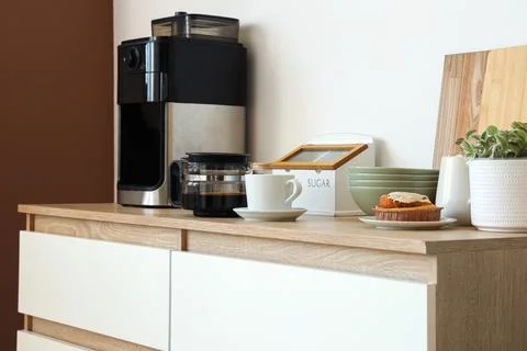 Modern kitchen counter with coffee maker, cup, muffin, and kitchenware Stock Photos