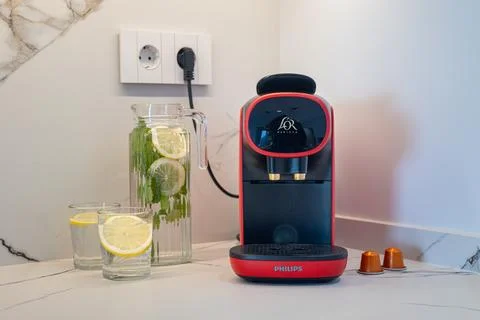 Modern kitchen counter with red coffee machine, lemon water and espresso ca.. Stock Photos