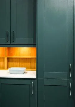Modern kitchen design featuring dark teal cabinets, wooden shelves with und.. Stock Photos