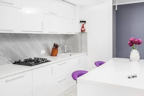 Modern kitchen with dining table and purple chairs Stock Photos