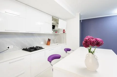 Modern kitchen with dining table and purple chairs Foto stock
