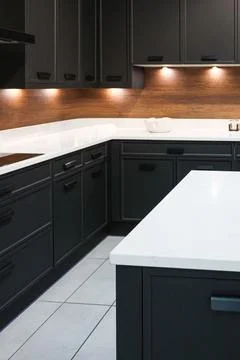 Modern kitchen interior with dark cabinets, white countertops, wood backspl.. Stock Photos