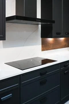 Modern kitchen interior with dark cabinets, white quartz countertop, black .. Stockfoto's