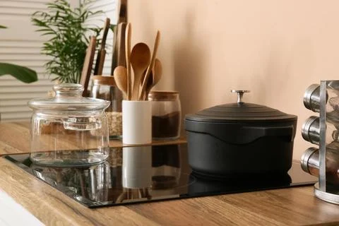 Modern kitchen interior with induction cooktop, cast iron pot, glass jar, and Stock Photos