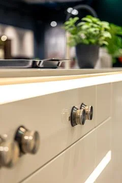 Modern kitchen interior with lighting. Control knobs on white cabinet. Stock Photos