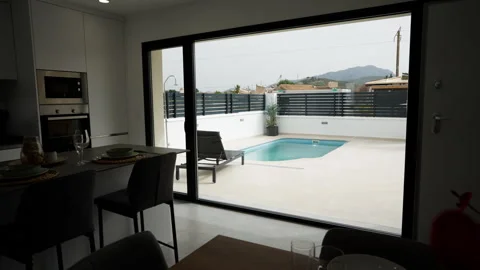 Modern kitchen interior with pool view and outdoor terrace area Stock Footage 334534482