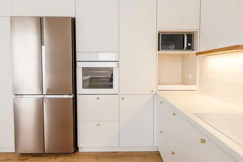 Modern kitchen interior. Stylish white kitchen cabinets with brass knobs, g.. Stock Photos