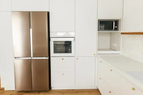 Modern kitchen interior. Stylish white kitchen cabinets with brass knobs, g.. Stock Photos
