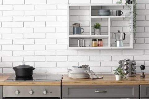 Modern kitchen interior with white brick wall, wooden countertop, induction c Stock Photos